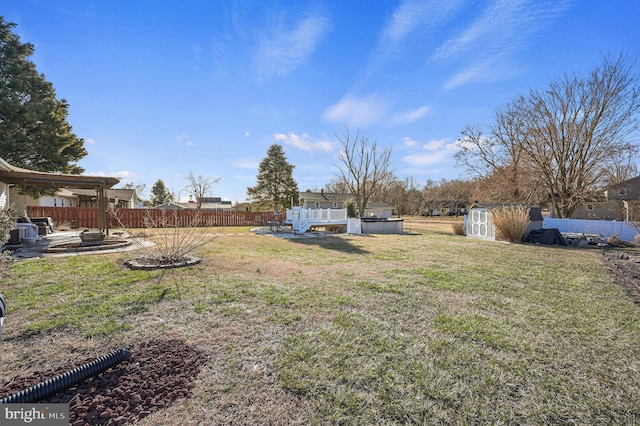 view of yard with a storage shed, fence, an outbuilding, and an outdoor fire pit