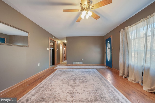 interior space with visible vents, baseboards, a ceiling fan, and wood finished floors