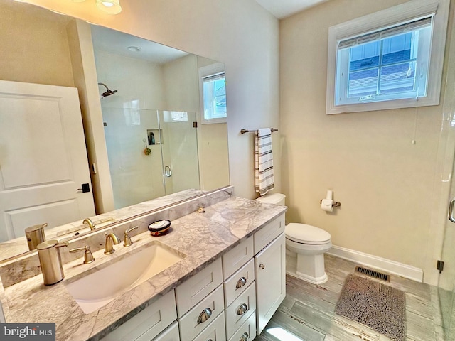 bathroom featuring a stall shower, toilet, vanity, baseboards, and wood finished floors