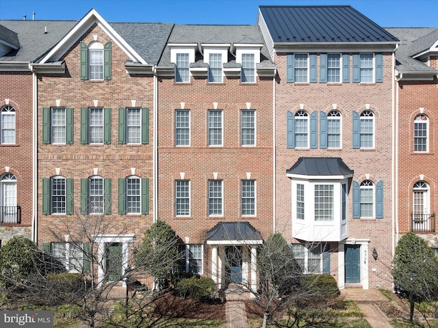 view of property featuring a standing seam roof and brick siding