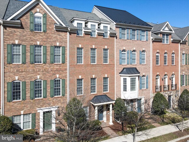 townhome / multi-family property featuring brick siding and a standing seam roof