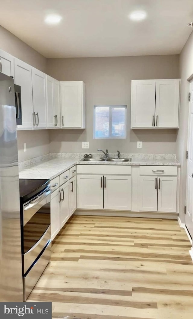 kitchen with white cabinets, appliances with stainless steel finishes, light countertops, and a sink