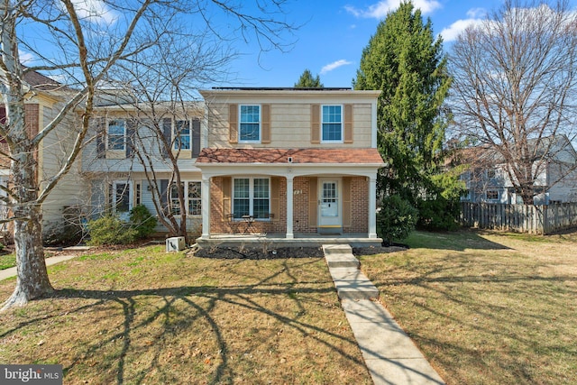 view of front facade featuring a front yard, covered porch, fence, and brick siding