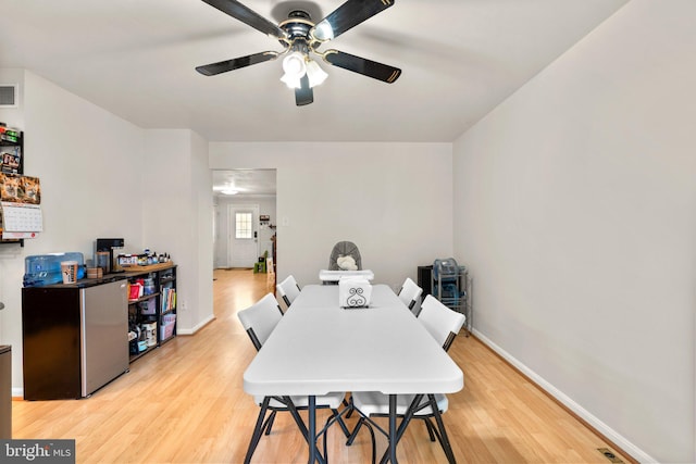 dining space featuring light wood-style flooring, baseboards, and a ceiling fan