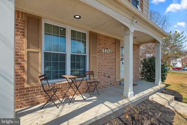 doorway to property with brick siding and a porch