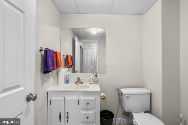 bathroom with a paneled ceiling, toilet, and vanity