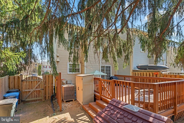 deck featuring cooling unit, fence, and a gate