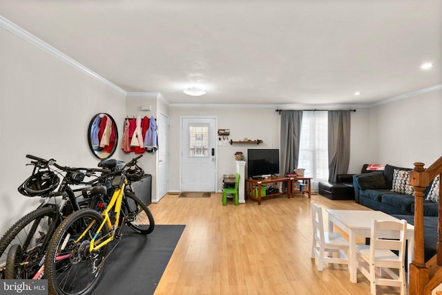 living area featuring light wood-type flooring, baseboards, and crown molding