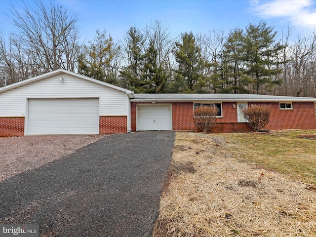 ranch-style home with a front lawn, a garage, brick siding, and driveway