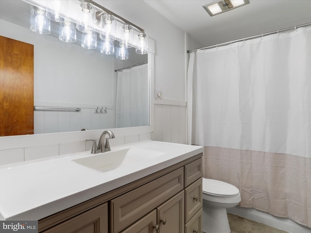 full bath featuring vanity, toilet, and a wainscoted wall