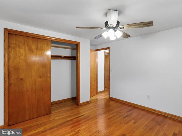 unfurnished bedroom featuring a closet, baseboards, wood finished floors, and a ceiling fan