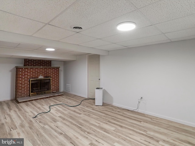 unfurnished living room featuring a fireplace, a paneled ceiling, baseboards, and wood finished floors