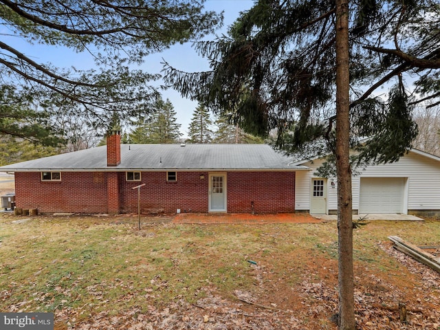 rear view of property with cooling unit, a lawn, an attached garage, and a chimney