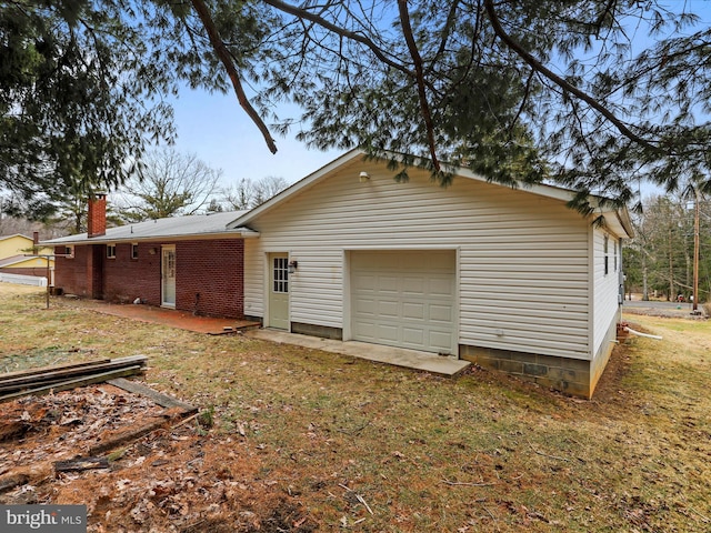 back of property featuring a yard, brick siding, a garage, and a chimney