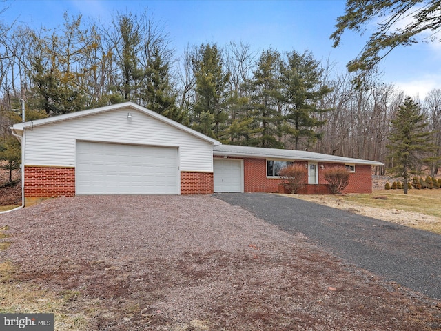 single story home featuring a garage, brick siding, and driveway