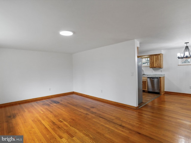 empty room featuring a chandelier, baseboards, and hardwood / wood-style flooring