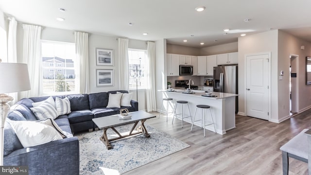 living area featuring recessed lighting, baseboards, and light wood-style flooring