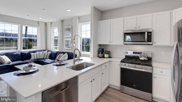 kitchen featuring open floor plan, appliances with stainless steel finishes, light countertops, and a peninsula