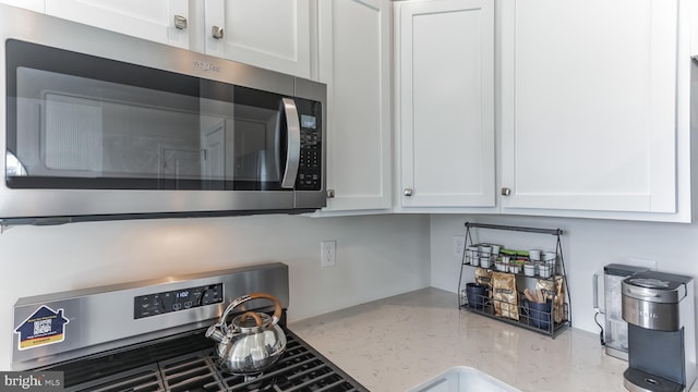 kitchen with white cabinets, light stone countertops, and appliances with stainless steel finishes