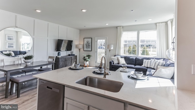 kitchen featuring open floor plan, plenty of natural light, dishwasher, and a sink