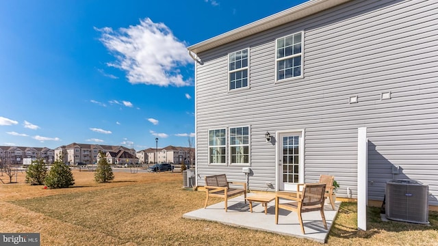 rear view of house featuring a patio, central air condition unit, a yard, and a residential view