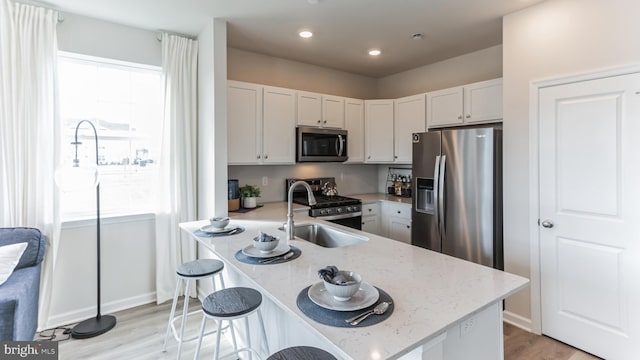 kitchen with plenty of natural light, light stone countertops, stainless steel appliances, and a sink