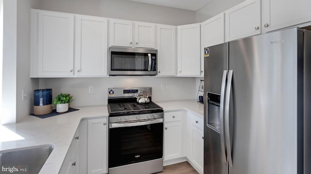 kitchen featuring white cabinets, stainless steel appliances, and light stone countertops