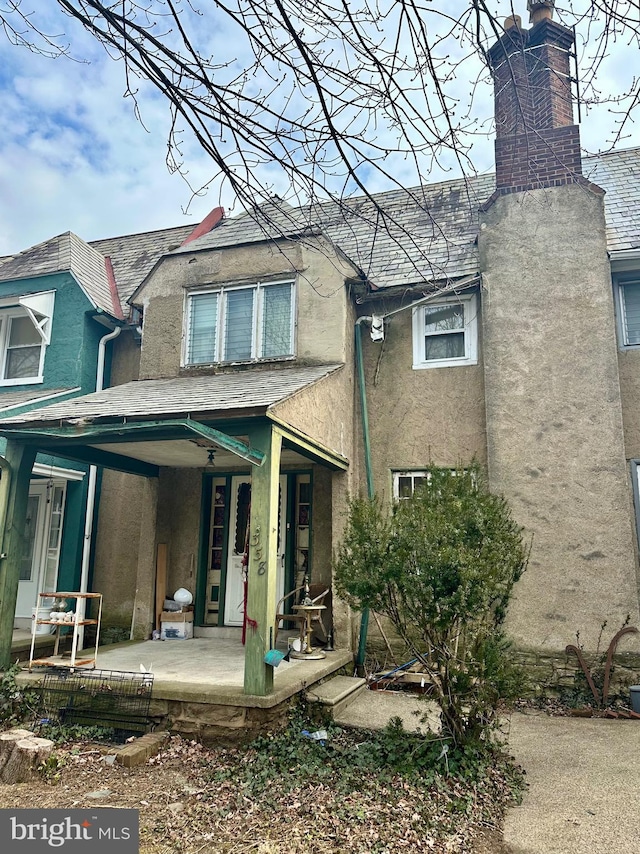 rear view of property with stucco siding and a chimney