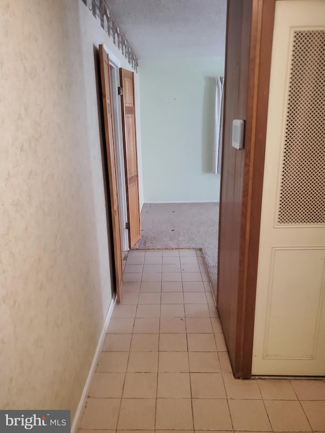 hall featuring light tile patterned floors, a textured ceiling, and a heating unit