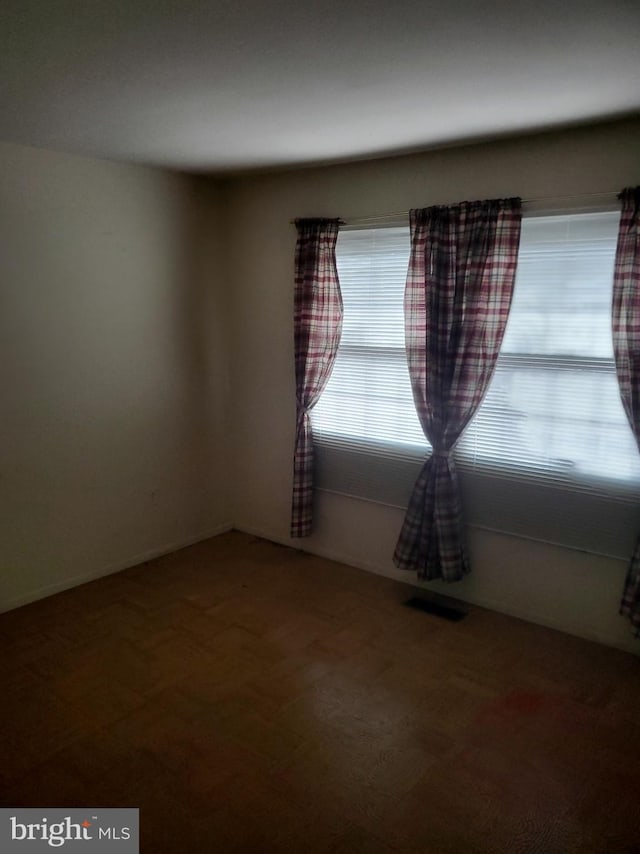 carpeted spare room featuring visible vents