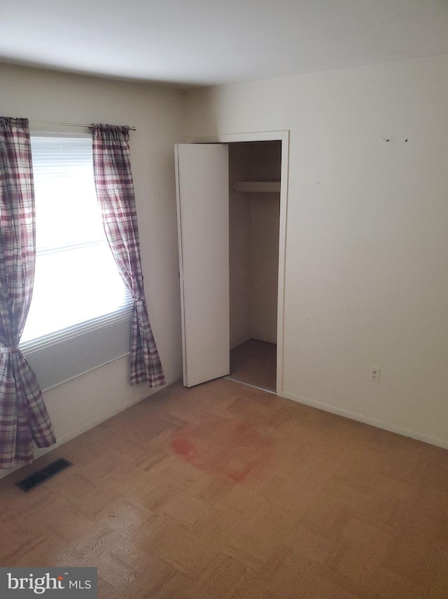 unfurnished bedroom featuring a closet, visible vents, and baseboards