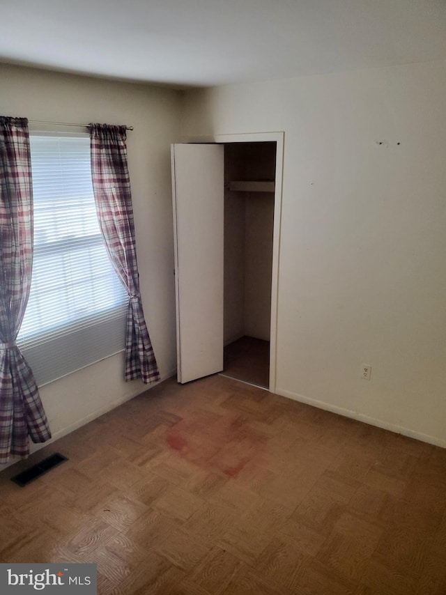 unfurnished bedroom featuring baseboards, visible vents, and a closet