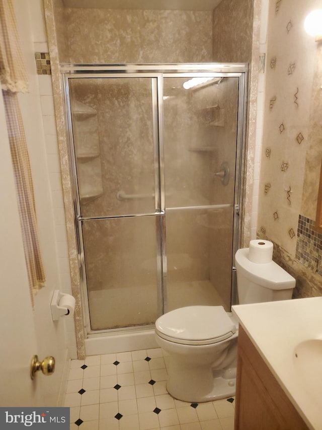 bathroom featuring vanity, toilet, and a stall shower