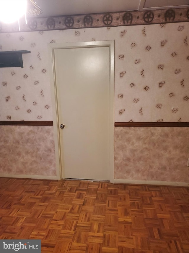 empty room featuring wallpapered walls and wainscoting