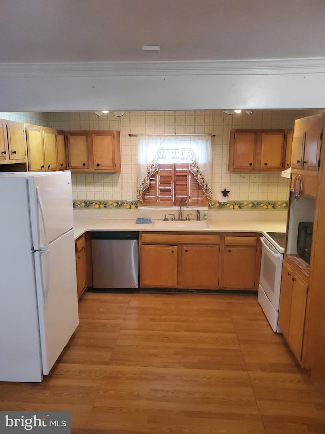 kitchen featuring ornamental molding, white appliances, light countertops, and a sink