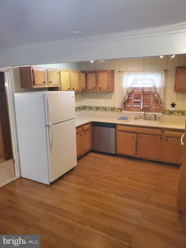 kitchen featuring crown molding, light countertops, freestanding refrigerator, and stainless steel dishwasher