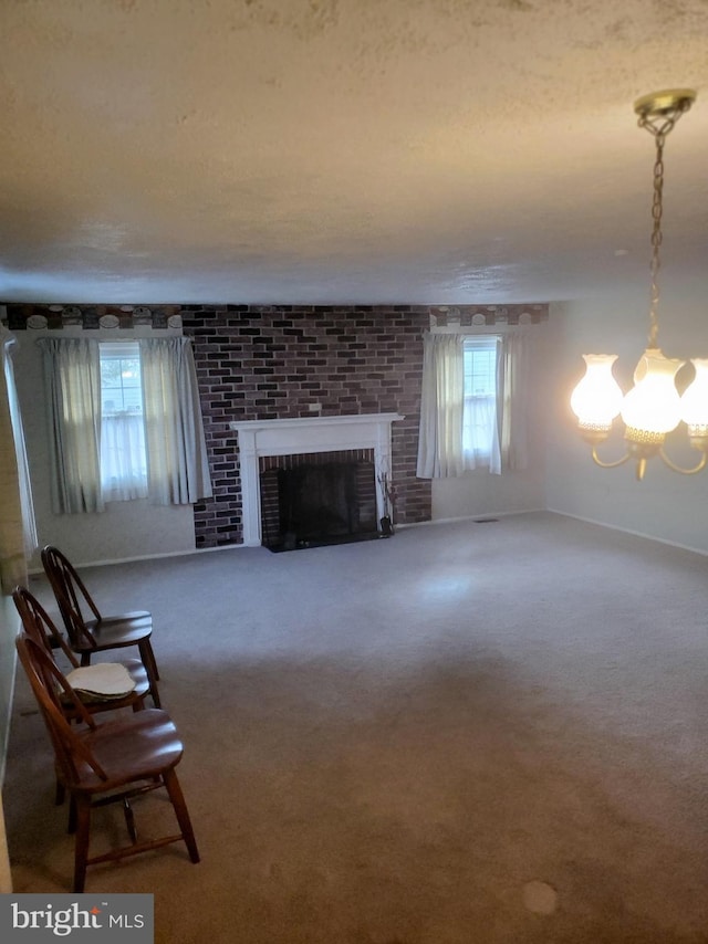 unfurnished living room with carpet flooring, a brick fireplace, a textured ceiling, and an inviting chandelier