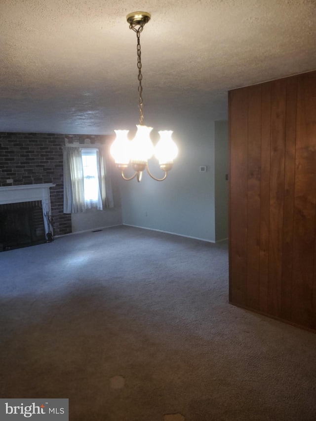 interior space featuring a textured ceiling, a brick fireplace, carpet flooring, and a chandelier