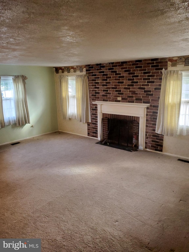 unfurnished living room featuring visible vents, a textured ceiling, carpet flooring, and a fireplace