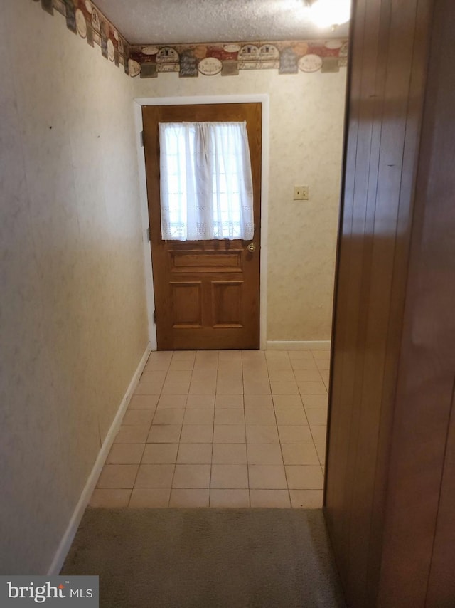 doorway featuring a textured ceiling and light tile patterned flooring