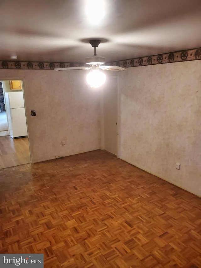 spare room featuring ceiling fan and parquet flooring