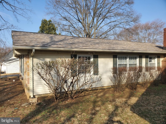 view of side of property featuring roof with shingles and a chimney