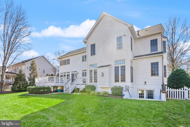 back of property with a yard, a wooden deck, and fence