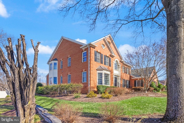 view of side of property featuring a lawn and brick siding