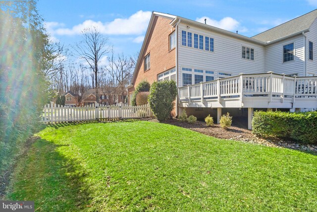 rear view of house with a lawn, a deck, and fence