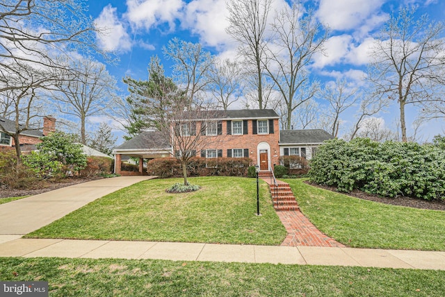 view of front of home featuring an attached carport, a front yard, brick siding, and driveway