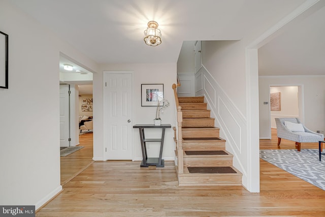 stairs with ornamental molding, baseboards, and wood finished floors