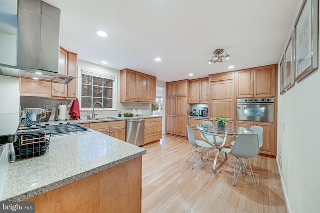 kitchen featuring light wood finished floors, recessed lighting, island exhaust hood, a sink, and stainless steel appliances