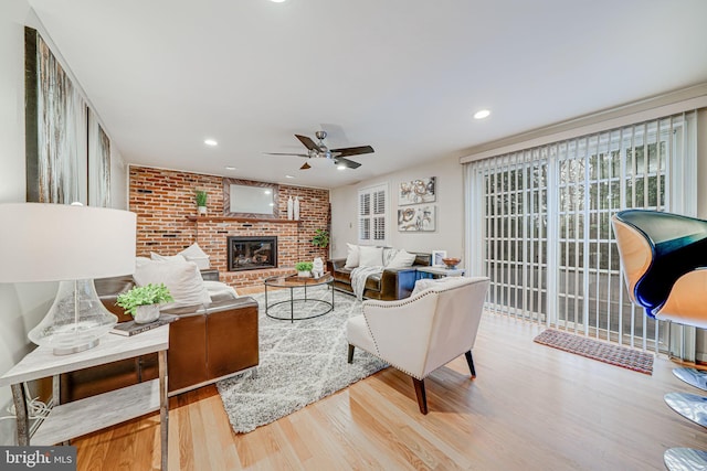 living room with wood finished floors, a brick fireplace, recessed lighting, and a ceiling fan