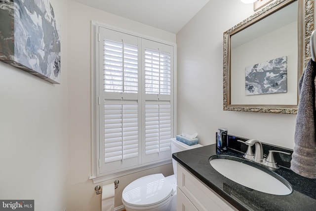 half bathroom featuring vanity and toilet